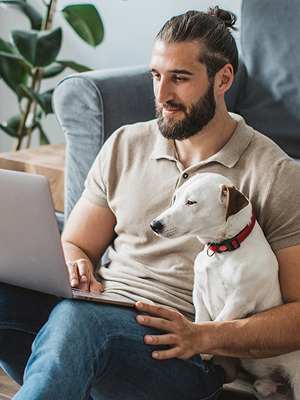 man sitting with dog looking at computer