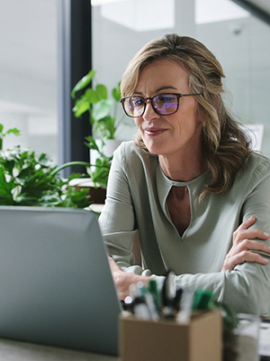 A lady with glasses looking at her laptop