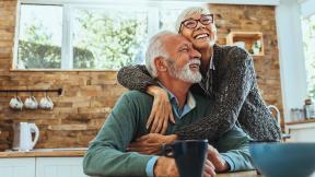 An older couple hugging in the kitchen. 