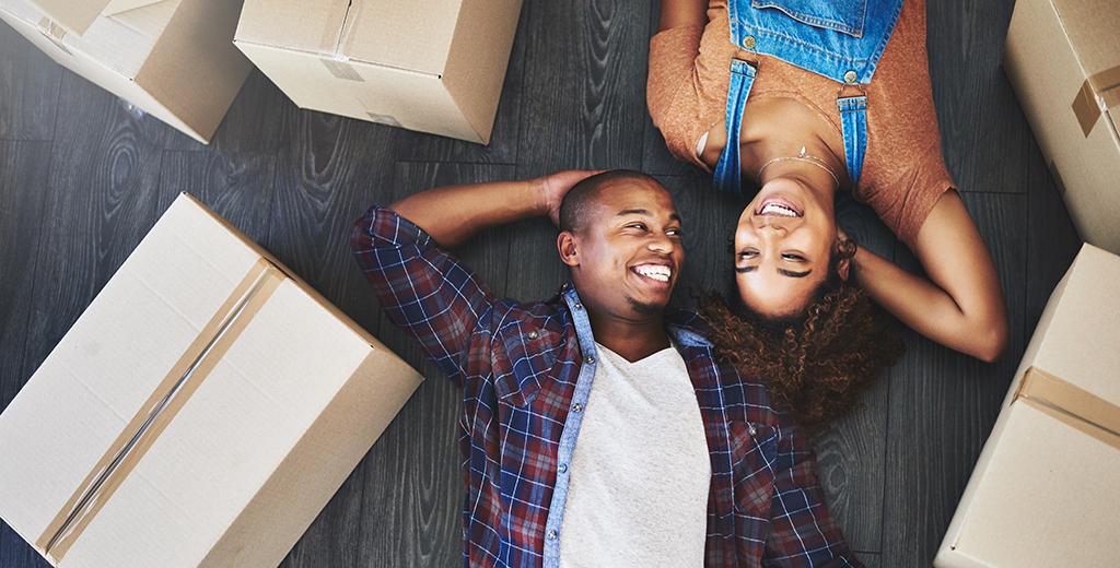 A couple taking a break from moving to lay on the floor together. 